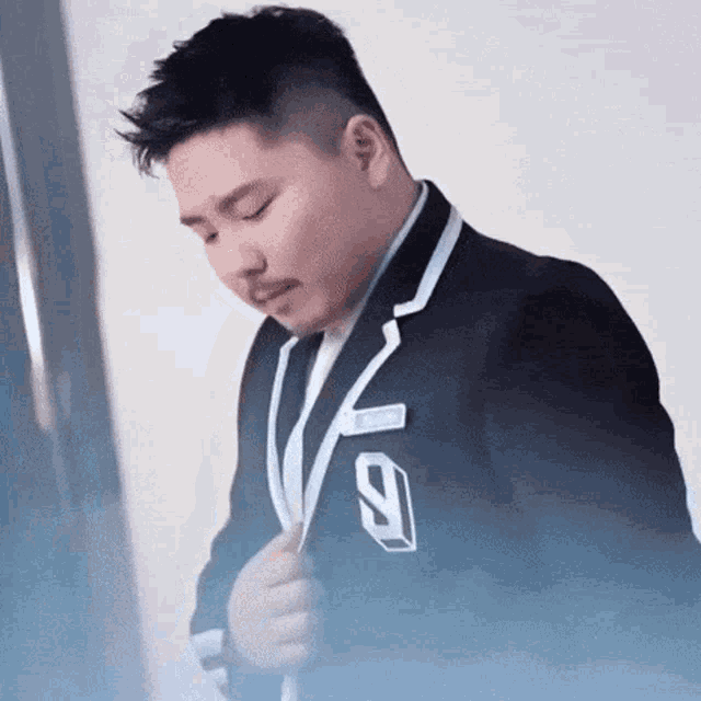 a man in a suit with the number 9 on his collar