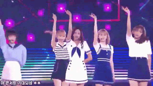 a group of girls are dancing on a stage with their arms in the air
