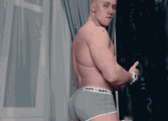 a man without a shirt is giving a thumbs up in a room