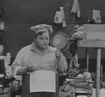 a black and white photo of a man in a chef 's hat