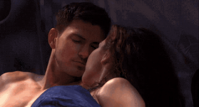 a man and a woman are kissing while laying in bed
