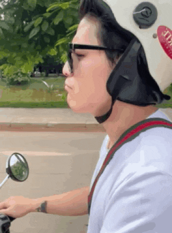 a man wearing a helmet and sunglasses is riding a motorcycle down the street .