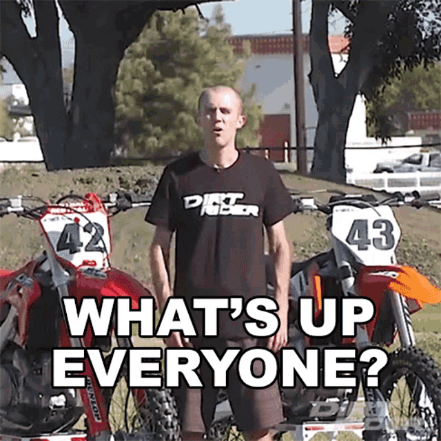 a man standing in front of two dirt bikes with the words what 's up everyone on the bottom