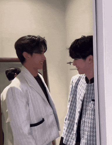 two men are standing next to each other in a room and looking at each other