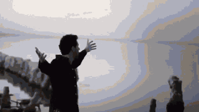 a man is standing in front of a lake with his arms outstretched .