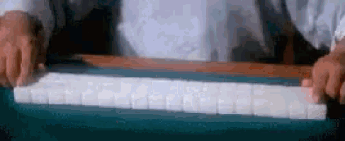 a person is playing mahjong on a table with a blue table cloth .