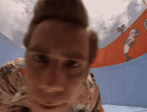 a close up of a person 's face with a baseball player on the wall behind him