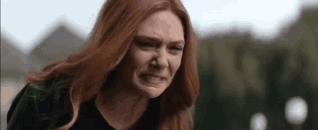 a close up of a woman with red hair making a silly face .
