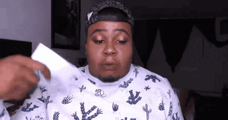 a man is holding a piece of paper in front of his face and making a funny face .