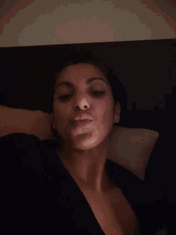a woman laying down with her head on a pillow with her eyes closed