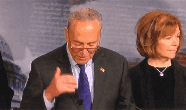 a man in a suit and tie giving a thumbs up while standing next to a woman