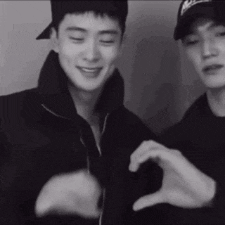 a couple of men are making a heart shape with their hands .