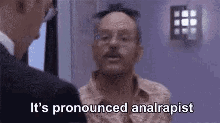 a man with glasses and a mustache is talking to another man in a suit .