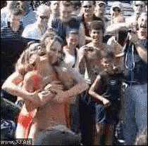 a woman in a bikini is being held by a man in a crowd of people