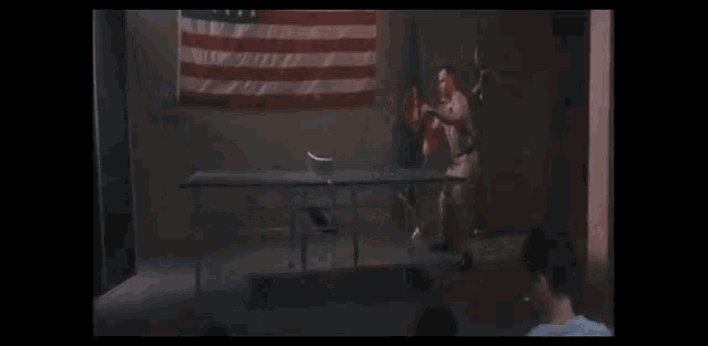 a group of people sitting in front of an american flag watching a man jumping in the air