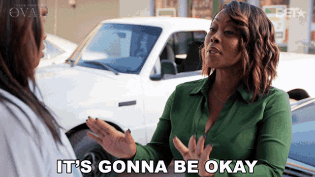 a woman in a green shirt says it 's gonna be okay in front of a white truck