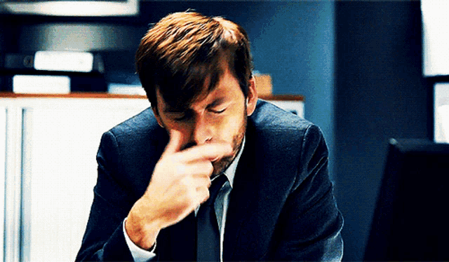 a man in a suit and tie is covering his nose