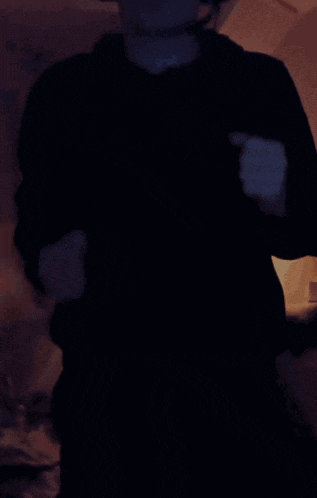a person wearing a black hoodie and a headset is dancing in the dark
