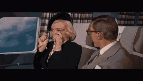 a man and a woman are sitting on a plane and the woman is wearing glasses