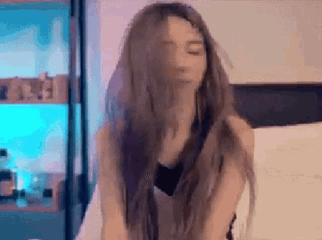 a woman with long hair is sitting on a bed .