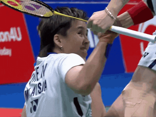 a badminton player wearing a white shirt with the word malaysia on the back