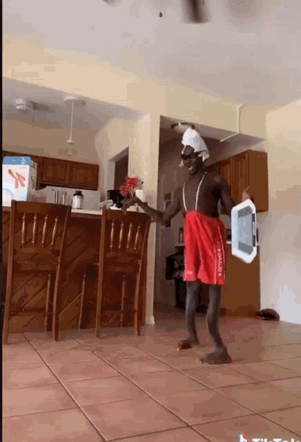 a man in red shorts is holding a tablet in a living room