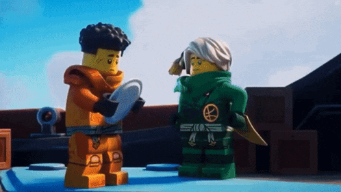 two lego ninjago characters are standing next to each other on a table .