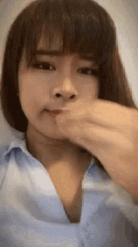 a woman in a blue shirt is covering her face with her hand