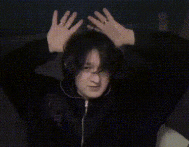 a man wearing headphones and a black jacket is making a face