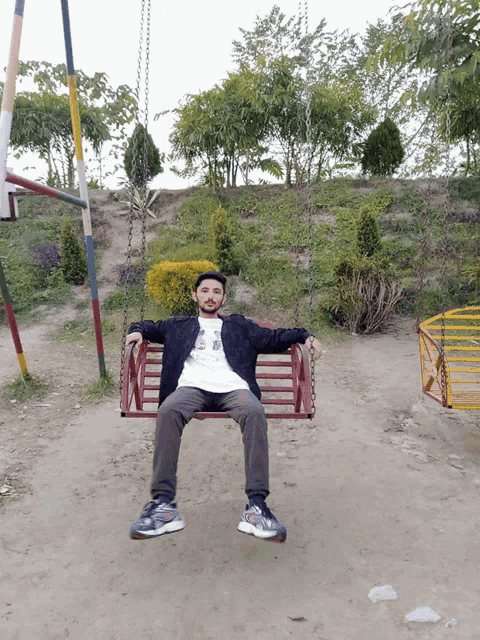 a man is sitting on a swing wearing a white shirt that says ' i love you ' on it