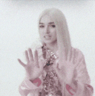 a woman in a pink jacket waving her hand