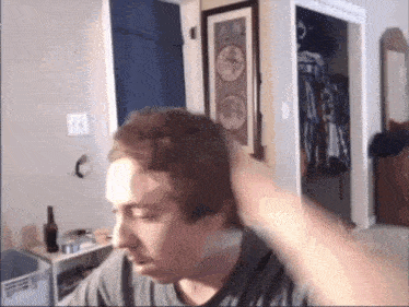 a man adjusts his hair in a room with a picture of a bicycle on the wall