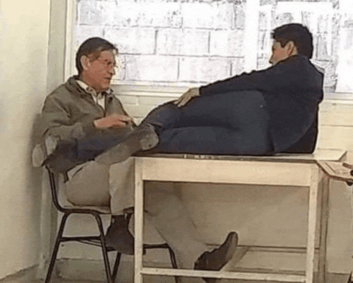 two men are sitting at a table with their feet on the table .