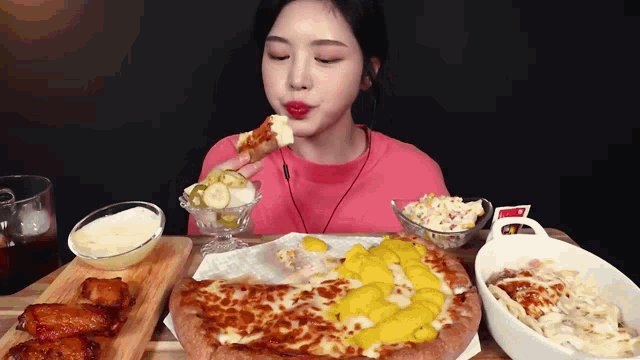 a woman in a pink shirt is eating a slice of pizza
