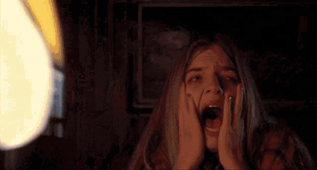a woman is screaming with her mouth open in front of a painting