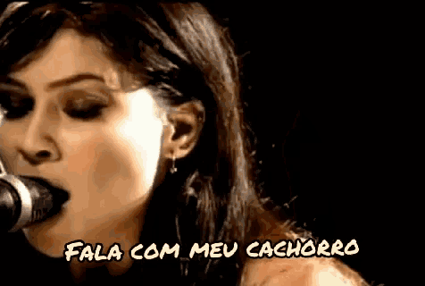 a woman singing into a microphone with the words fala com meu cachorro on the bottom