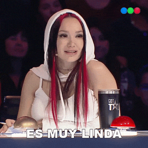 a woman with red hair is sitting in front of a cup that says got talent