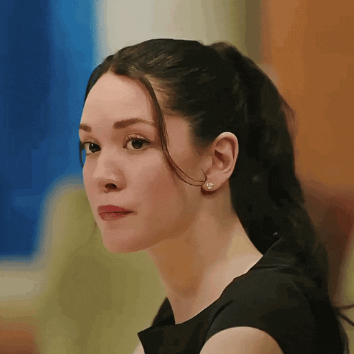 a woman with a ponytail and pearl earrings