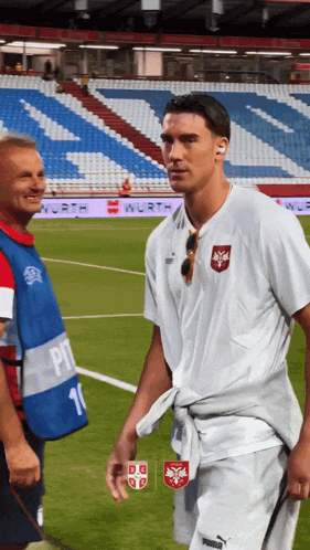 a man walking on a soccer field with a man wearing a vest with the number 11 on it