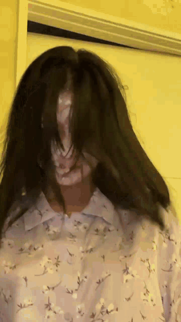 a woman wearing a floral shirt has her hair covering her face