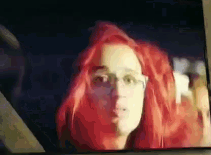 a woman with red hair and glasses is looking at the camera .