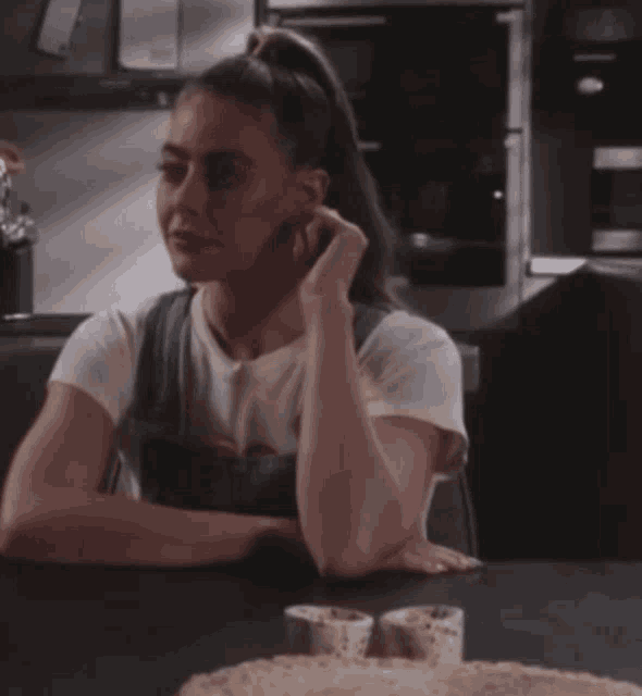 a woman sits at a table with her hand on her face