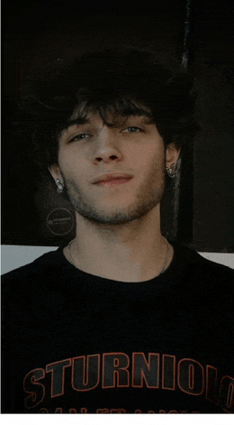 a young man with a beard wears a black shirt that says sturniolo