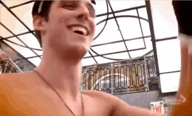 a man without a shirt is smiling in front of a balcony .