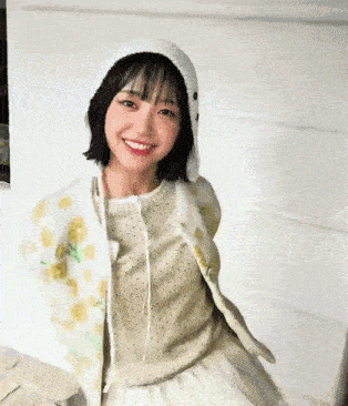 a young woman wearing a white hat and a floral jacket is smiling .