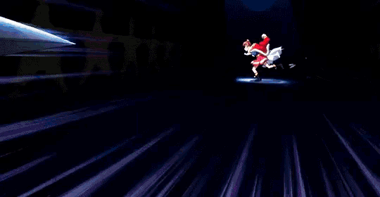 a girl in a red dress is jumping in the air in a dark room .