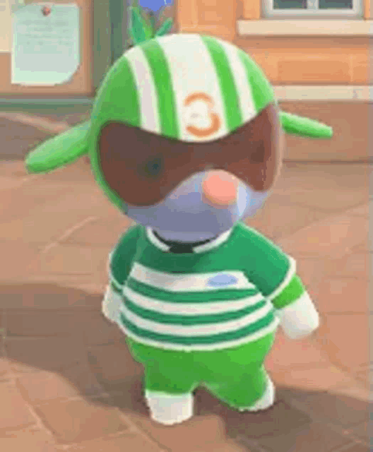 a stuffed animal wearing a green and white striped shirt and a green helmet is standing on a sidewalk .