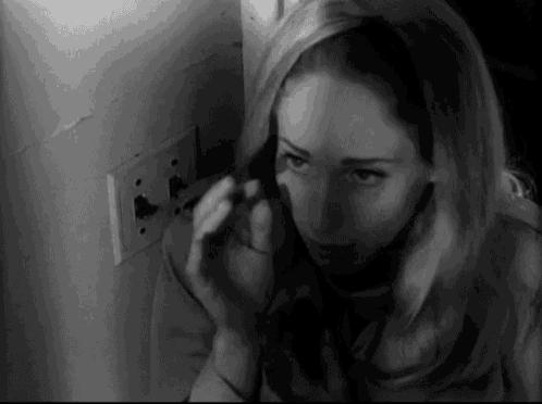 a black and white photo of a woman applying makeup .