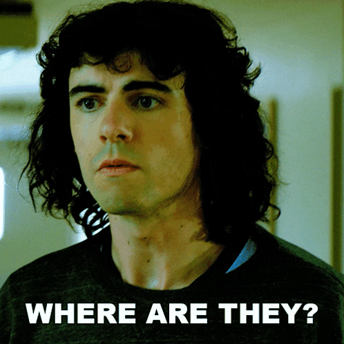 a man with curly hair is standing in front of a sign that says where are they on it