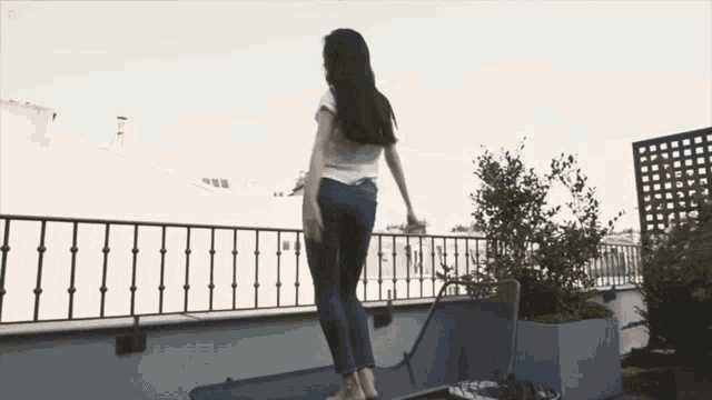 a woman is standing on a balcony with a fence